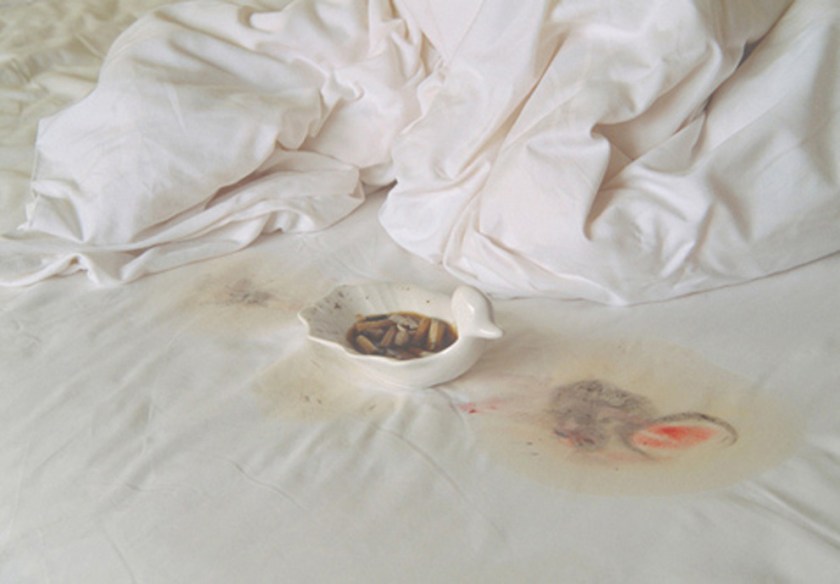 Dirty ashtray on white bedsheets